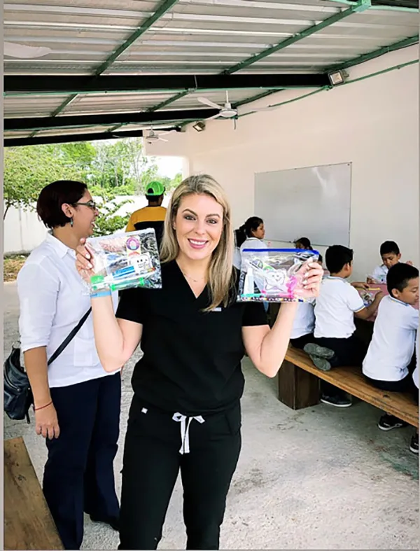 a woman holds up bags of school supplies